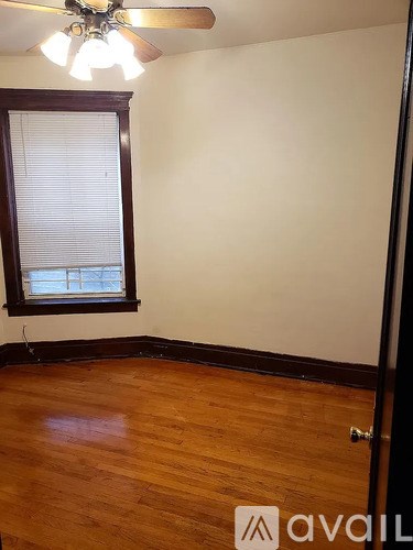 A room with wooden floors and a window with blinds.