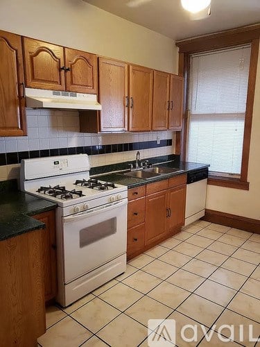 A kitchen with a white stove and wooden cabinets.