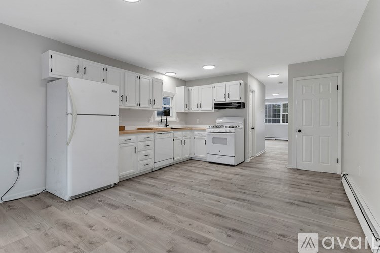 A kitchen with white appliances and wooden floors.