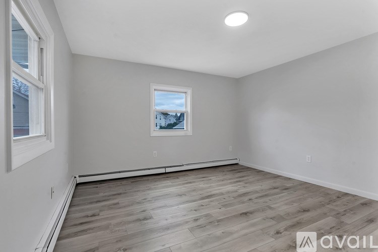 A room with wooden flooring and a window showing a view of a house.