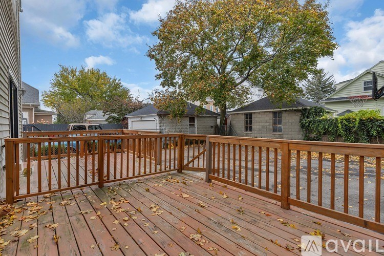 A wooden deck with a railing and fallen leaves on it.