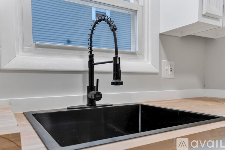 A kitchen sink with a black faucet and a window above it.