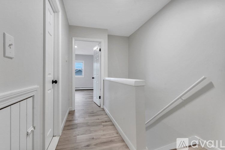 A hallway with a wooden floor and white walls.