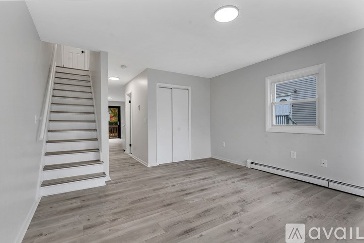 A spacious room with wooden floors and a staircase leading to another level.