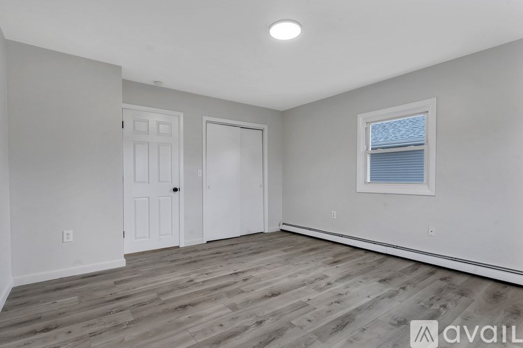 A spacious room with wooden flooring and white walls.
