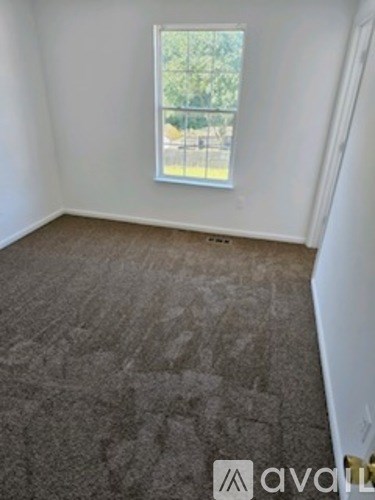 A room with a carpeted floor and a window.