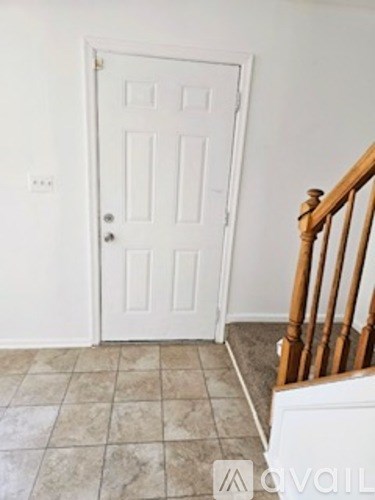 A white door with a tiled floor and a wooden staircase.