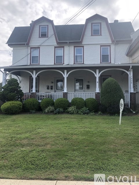 A white house with a red roof and a sign in front.
