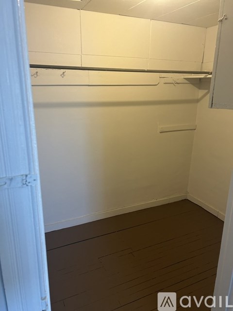 A white door is open to a small, empty room with a white wall and a white shelf.