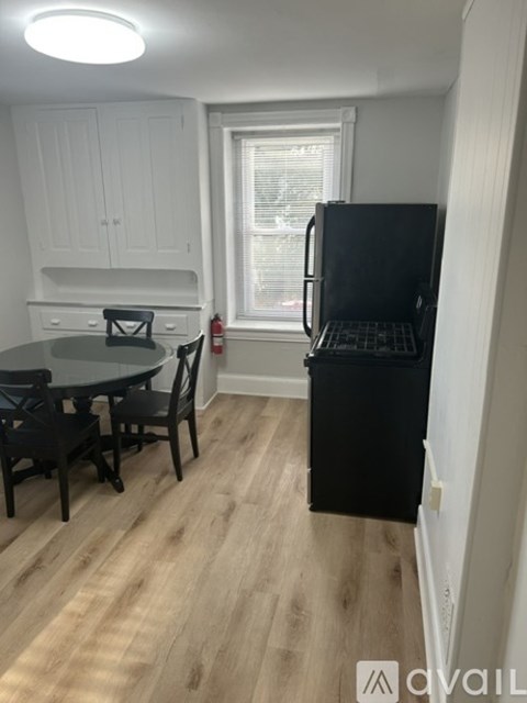 A kitchen with a black fridge and wooden floors.