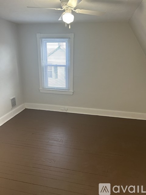 A room with a window and wooden flooring.