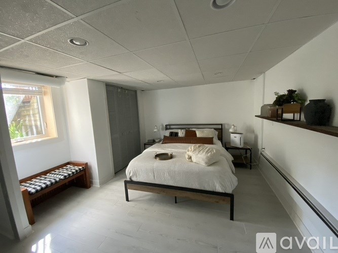 A bedroom with a bed, nightstand, and window.