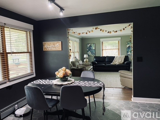 A dining room with a table set for two and a couch in the background.