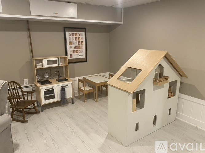 A dollhouse with a kitchen and a dining table is displayed.