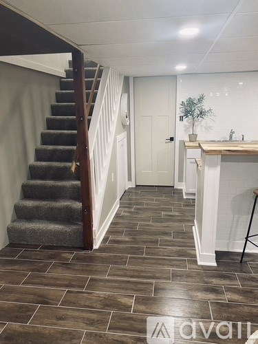 A hallway with a staircase and a small table with a plant on it.