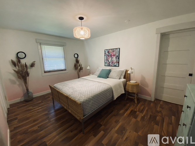 A bedroom with a bed, a nightstand, and a plant.