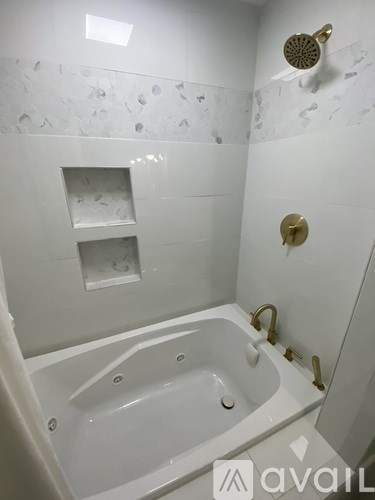 A white bathroom with a jacuzzi tub and a shower head.