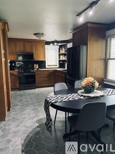 A kitchen with a table set for two and a vase of flowers on the table.
