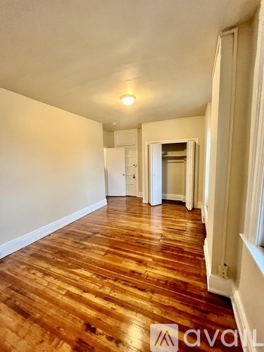 A long hallway with wood floors and white walls.