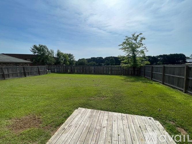 A backyard with a wooden deck and a fence.