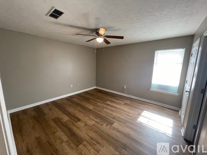A room with a ceiling fan and wooden flooring.