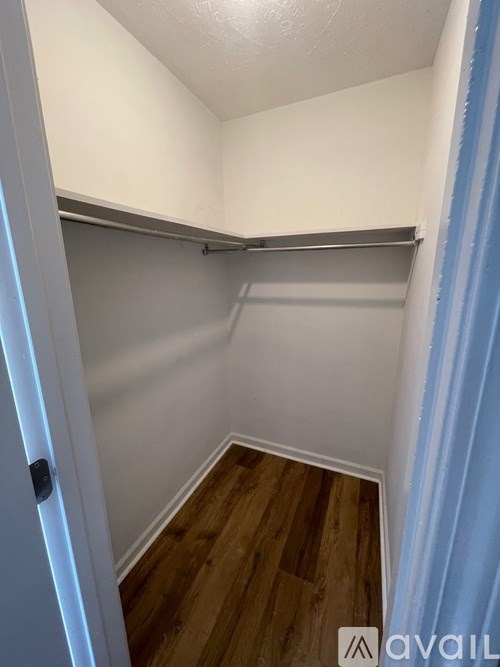 A small, empty room with a wooden floor and white walls.