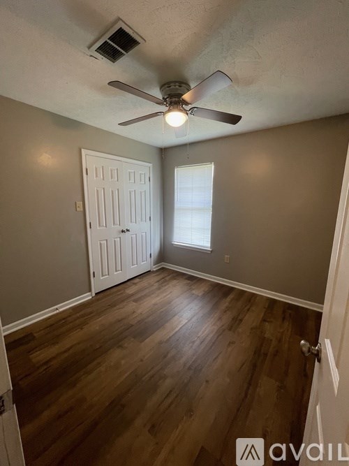 A room with a ceiling fan and wooden flooring.