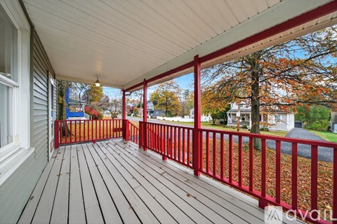 A wooden deck with red railings overlooks a residential street.