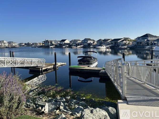 A boat is docked at a pier with houses in the background.