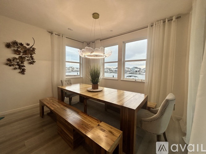 A dining room with a wooden table and bench, a hanging light fixture, and a decorative plant on the table.