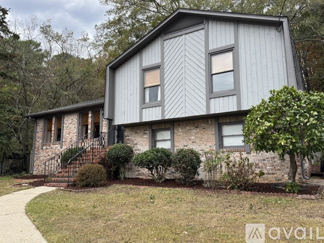 A grey house with a black fence and a tree in front.