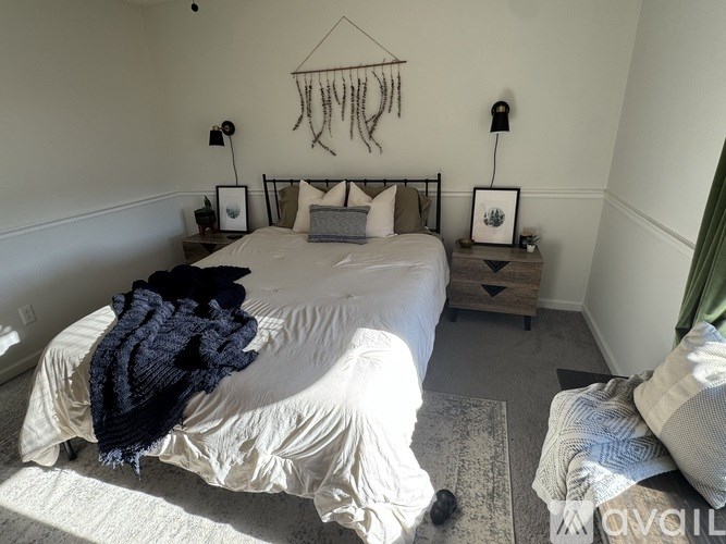 A bedroom with a bed, a cat, and a wall hanging.