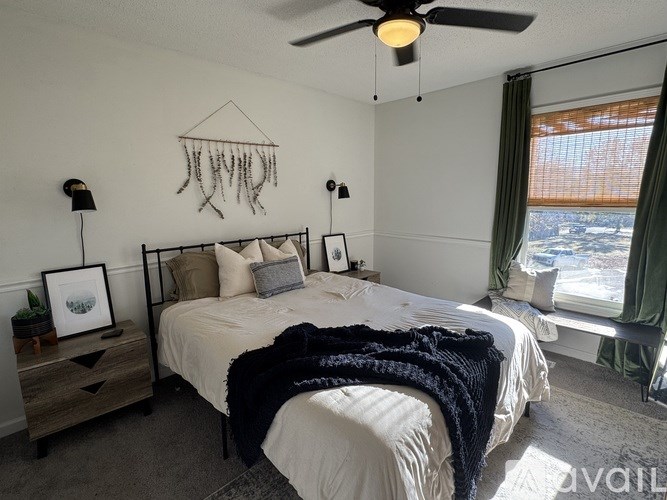 A bedroom with a bed, a ceiling fan, and a window with a view of the outside.