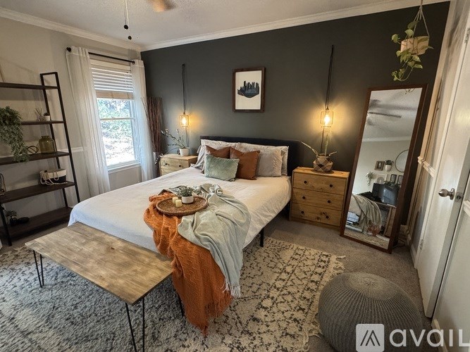 A bedroom with a bed, a nightstand, a chair, and a window.