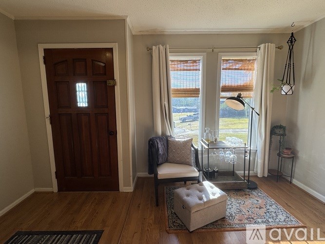 A room with a wooden door and a window with white curtains.