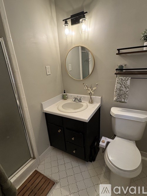 A bathroom with a toilet, sink, mirror, and shelves.