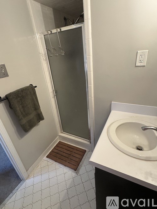 A bathroom with a white sink and a glass shower door.