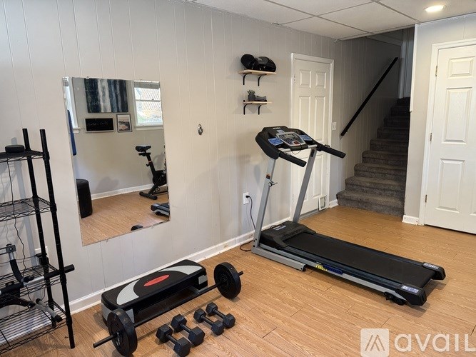 A room with a treadmill, weights, and a mirror.