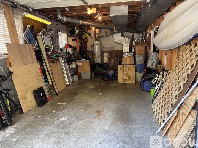 A cluttered garage with various items stored on the walls and floor.