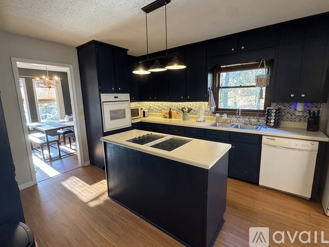 A kitchen with black cabinets and a white island.