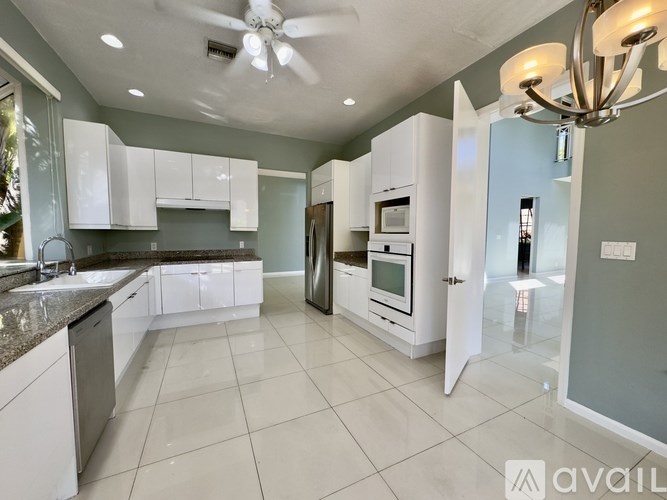 A modern kitchen with white cabinets and appliances.