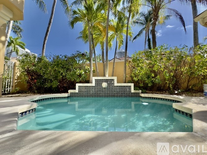A pool surrounded by palm trees and a house.