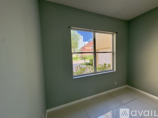 A room with a window showing a view of a street and buildings outside.