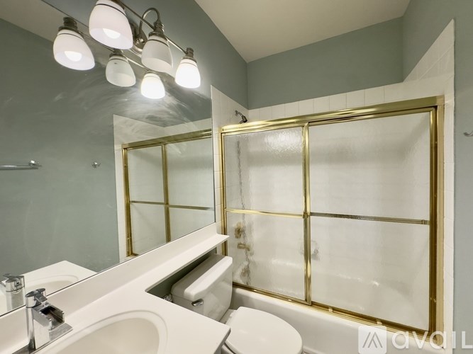 A bathroom with a white sink, gold-framed mirror, and a white toilet.