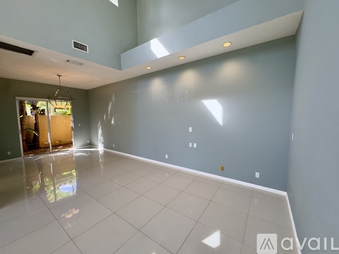 A spacious room with a white tiled floor and a ceiling fan.