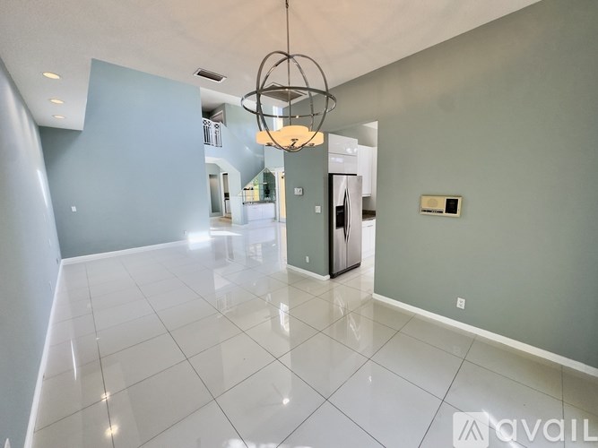 A spacious room with a white tiled floor and a chandelier hanging from the ceiling.