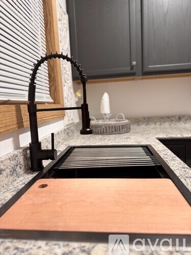 A kitchen sink with a black faucet and a wooden countertop.