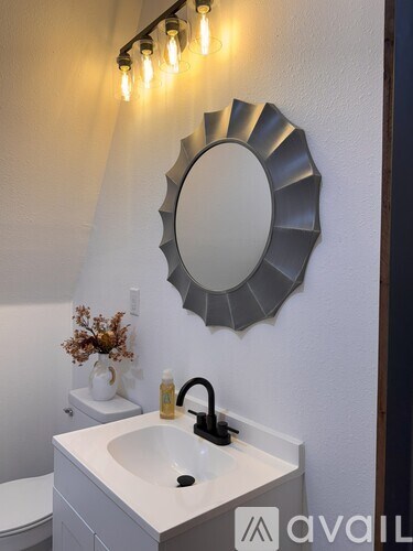 A bathroom with a sink, mirror, and lights.