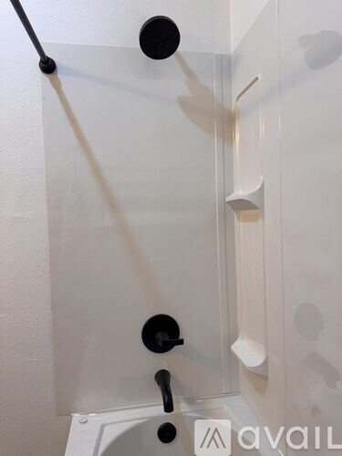 A white bathroom with a glass shower door and a black handle.