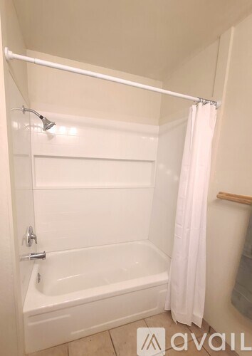 A white bathroom with a tub and a shower curtain.